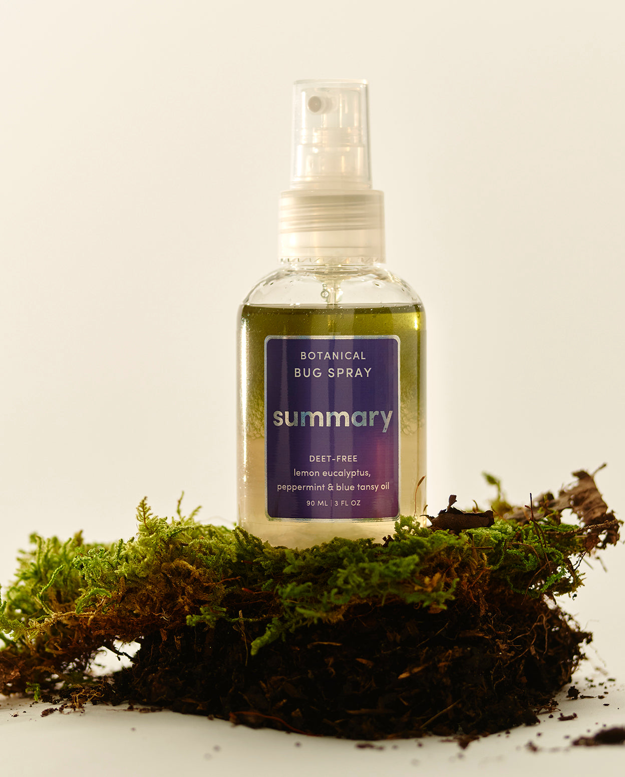 A spray bottle labeled 'SUMMARY' with a purple cap, containing a botanical bug spray made with natural ingredients.