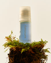 A roll-on bottle of COOL DOWN MUSCLE GEL with a stainless-steel roller-ball applicator, placed on a bed of moss.