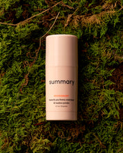 A travel-friendly mini size deodorant stick placed on a green mossy surface.
