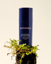 A blue stick deodorant with 'summary' written on it, placed on a bed of moss.